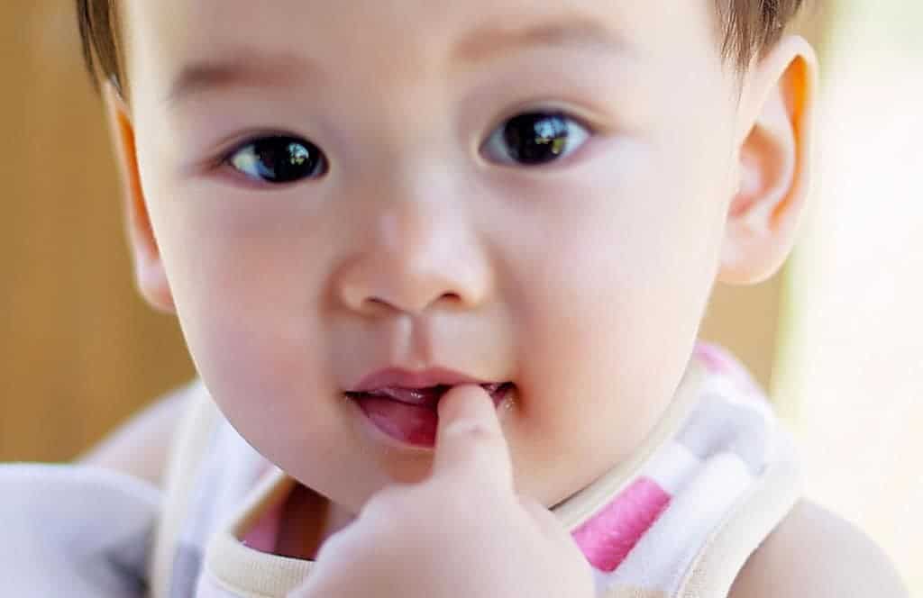 Asian one year old with finger in mouth closeup