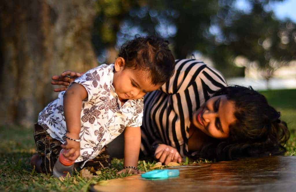 Indian mother on grass talking to infant