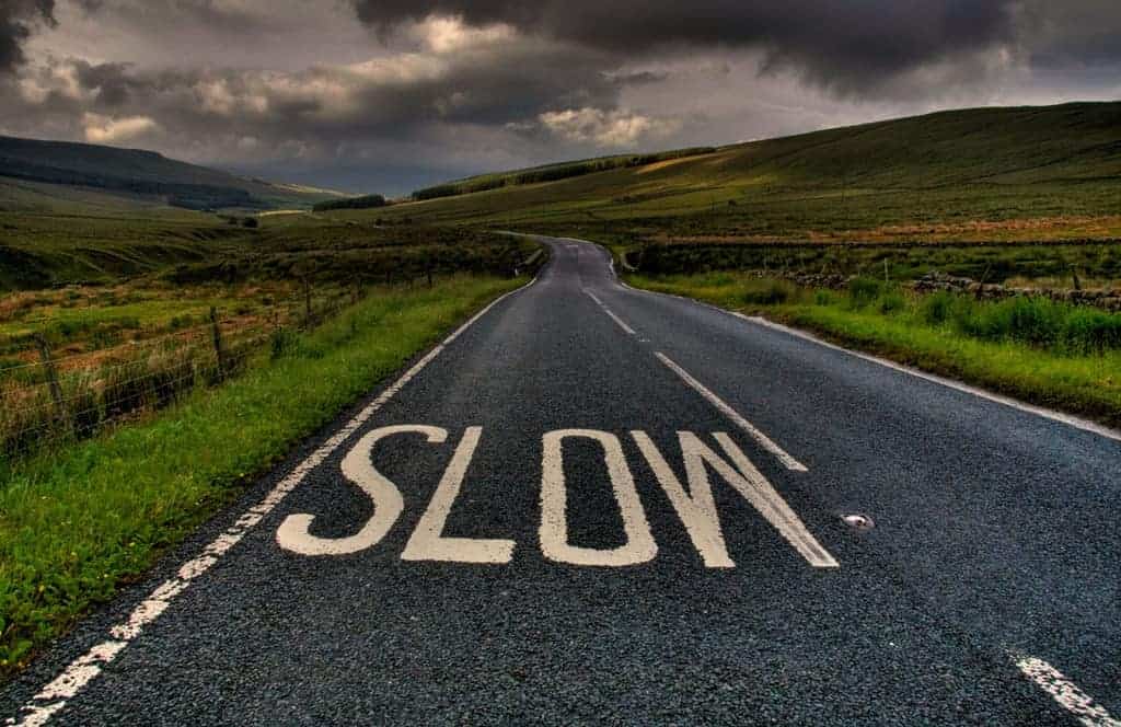 Country Road in Thunderstorm with SLOW Sign
