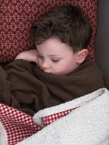 Sleeping sick toddler snuggled in blanket