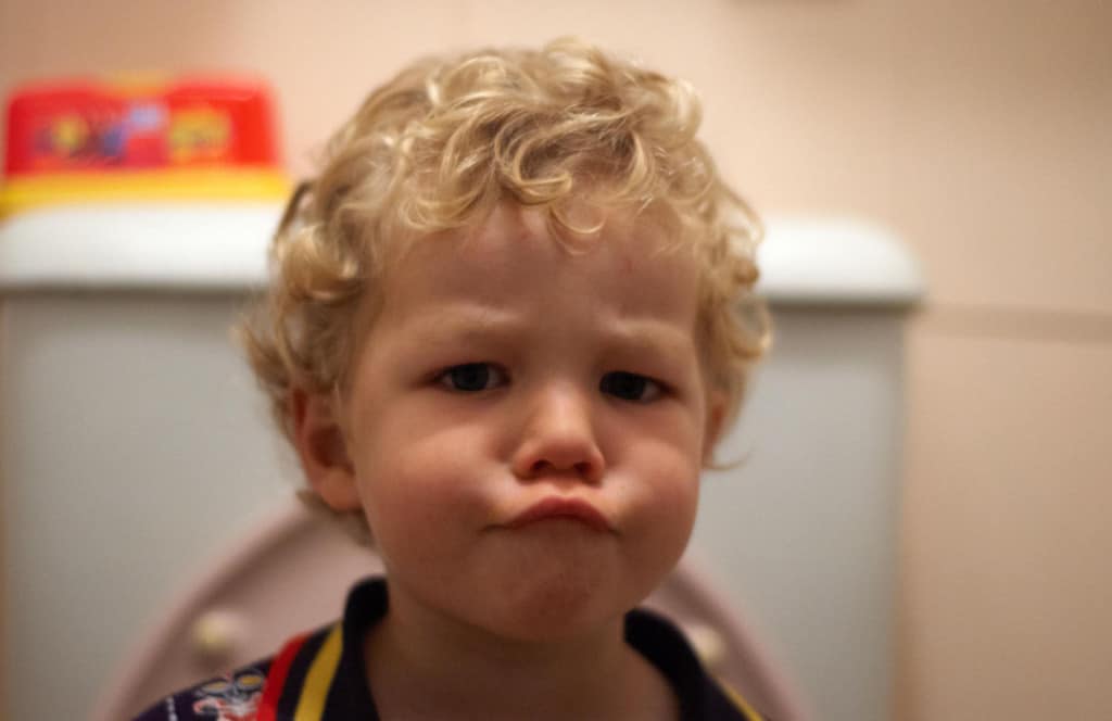 Toddler scowling angry on potty while toilet training