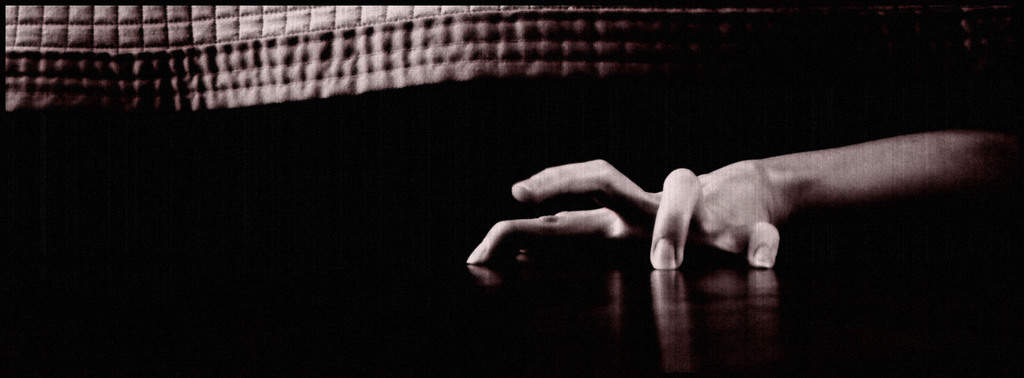 Black and White Photo of Hand sneaking out from under a bed
