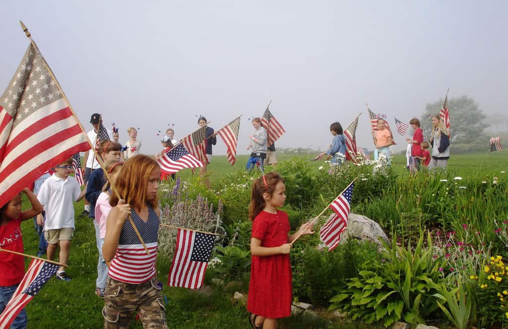 New Hampshire 4th of July Parade with Kids Carrying Flags through Grass