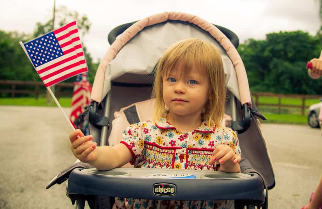 Toddler girl in stroller waving flag