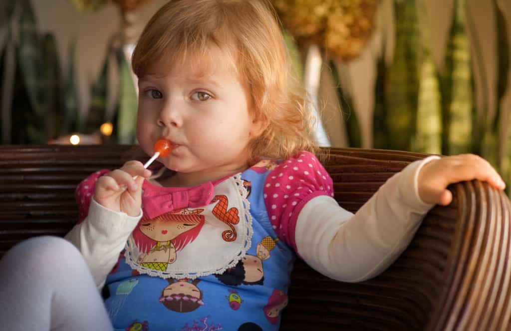 Toddler with lollipop looking skeptical