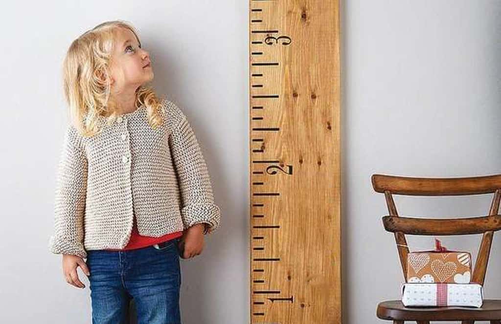 Girl looking up at growth chart measuring height.